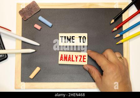 Time To Analyze text concept written on wooden cubes blocks lying on a light table next to calculator and pen. Stock Photo