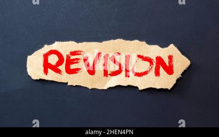 Beneath the torn strip of kraft paper attached with a red button is a white paper labeled REVISION. Stock Photo