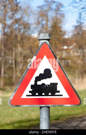 Railroad Level Crossing Sign without barrier or gate ahead the road, beware of train roadside steam engine locomotive signage road sign on signpost po Stock Photo