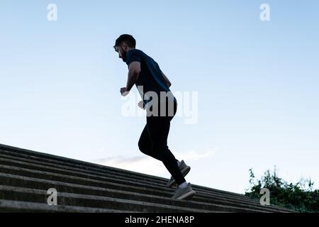 Unrecognizable young man running upstairs on city stairs Stock Photo
