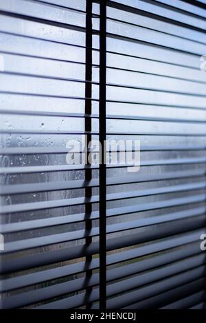 Metal blinds on windows in rainy weather Stock Photo