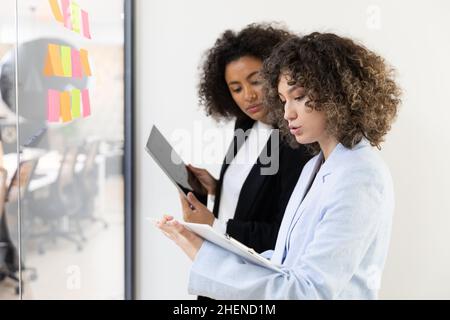 Multicultural coworkers using white board and doing brainstorming together. Co-working concept Stock Photo