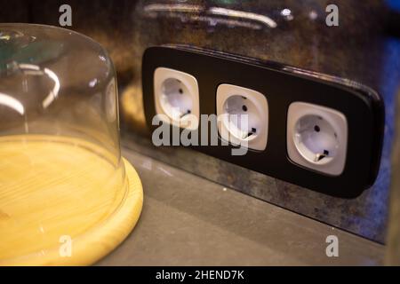 A white round electrical socket in a dark wooden frame is mounted ...