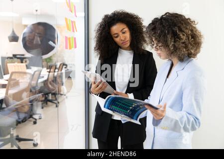 Multicultural coworkers using white board and doing brainstorming together. Co-working concept Stock Photo