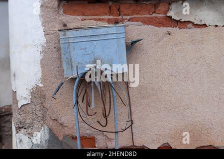 A very old metal water bucket with a faucet hanging on the wall of the house outdoor Stock Photo