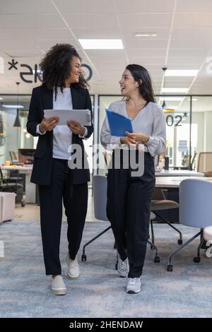 Multicultural coworkers walking in the office and having a conversation. Stock Photo