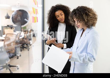 Multicultural coworkers using white board and doing brainstorming together. Co-working concept Stock Photo