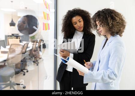 Multicultural coworkers using white board and doing brainstorming together. Co-working concept Stock Photo