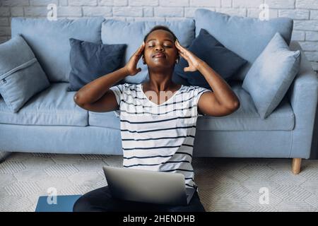 African american woman suffering from headaches while working online from home. Online lifestyle. Stock Photo