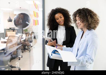 Multicultural coworkers using white board and doing brainstorming together. Co-working concept Stock Photo