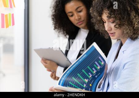 Multicultural coworkers using white board and doing brainstorming together. Co-working concept Stock Photo