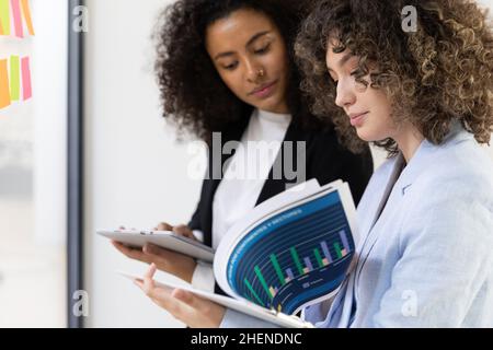Multicultural coworkers using white board and doing brainstorming together. Co-working concept Stock Photo