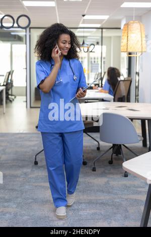 Young african american nurse wearing blue uniform smiling and talking on the phone. Stock Photo