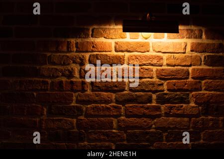 Brick wall illuminated by warm light from a lamp Stock Photo