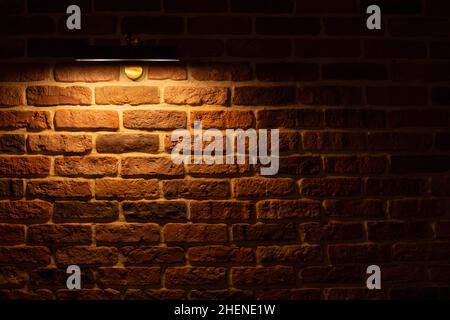 Brick wall illuminated by warm light from a lamp Stock Photo
