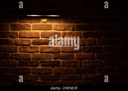 Brick wall illuminated by warm light from a lamp Stock Photo