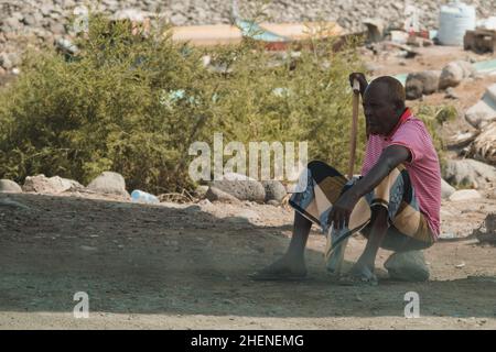 Djibouti, Djibouti - May 21, 2021: A Djiboutian man sitting on a stone. Editorial shot in Djibouti. Stock Photo