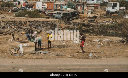 Djibouti, Djibouti - May 21, 2021: Djiboutian children drinking water from a water well in junk yard in Djibouti. Editorial shot in Djibouti. Stock Photo