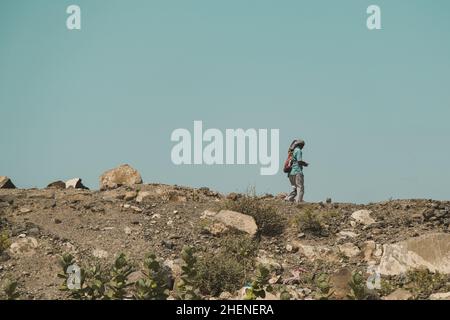 Djibouti, Djibouti - May 21, 2021: A Djiboutian alone man walking in the barren land. Editorial shot in Djibouti. Stock Photo