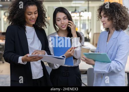 Pretty business women wearing formal wear smiling and having a conversation in the office. Stock Photo