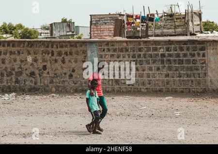 Djibouti, Djibouti - May 21, 2021: Two Djboutian brothers walking in front of a wall in Djibouti. Editorial shot in Djibouti. Stock Photo