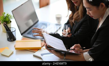 An Asian businesswomen discussing new ideas, brainstorming and taking a notes on notebook in the office. Stock Photo