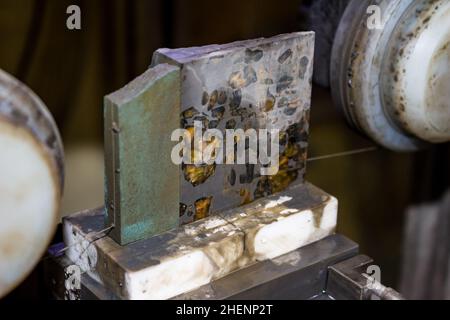 Sawing of the Pallasite iron-stone meteorite with a thin diamond thread. Inclusions of the yellow mineral olivine in a meteorite Stock Photo