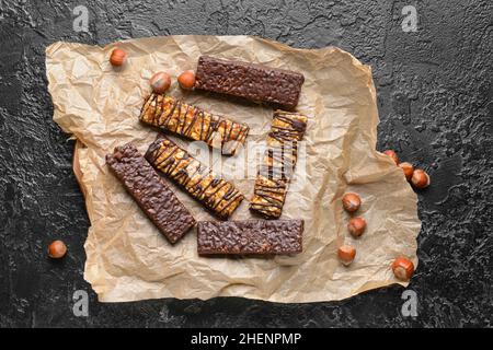 Parchment with tasty chocolate nut bars on dark background Stock Photo