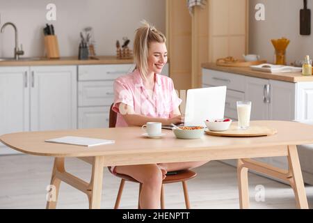 Pretty young woman using laptop in kitchen Stock Photo
