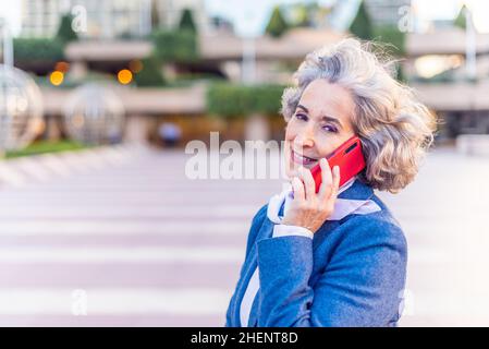 mature businesswoman smiling at camera while attending on the phone Stock Photo