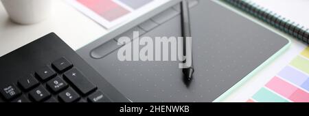 Graphic tablet with stylus and color palette on table Stock Photo