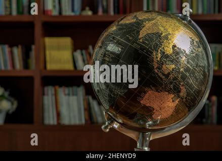 Chiang Rai,Thailand - Sep 06, 2020 : Replica globe on the background of bookshelves in library with copy space. No focus, specifically. Stock Photo