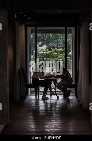 Chiang Mai,Thailand - Sep 07, 2020 : Shot of young adults sit and relaxing in a cafe and using mobile phone. Young man and woman at cozy coffee shop,