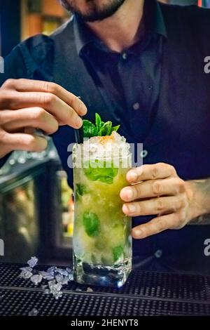 a bartender finishing a tasty freshly made mojito cocktail by adding straws Stock Photo