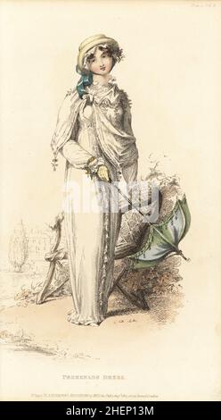 Regency woman strolling in the grounds of a stately home. Promenade dress of jaconot muslin trimmed with plaited muslin, white satin hussar cloak, Lavinia straw hat over a small lace cap. Gloves, rosary bracelet, and parasol. Designed by milliner Mrs Elizabeth Gill, 1 Cork Street, Burlington Gardens. Plate 12, Vol. 8, August 1 1812. Handcoloured copperplate engraving perhaps by Thomas Uwins from Rudolph Ackermann's Repository of Arts, London. Stock Photo