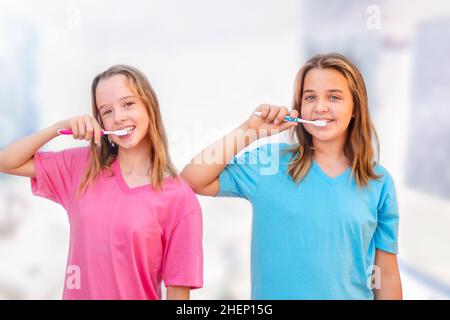 Teenage girls brush their teeth in the bathroom together in the morning Stock Photo