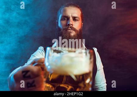 bearded man holding out mug of draft beer to the camera. Drinking concept. Stock Photo