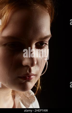 sad woman crying, looking aside on black background, closeup portrait Stock Photo