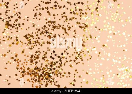 Composition with gold colored stars confetti scattered on a beige background. Stock Photo