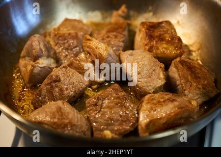 Pork chops (sirloin) searing in a stainless steel pan on the stove Stock Photo