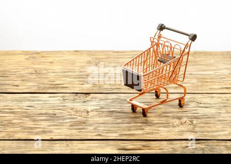 Copper colored metal shopping basket on striped textured wooden background surface. Copy space. Stock Photo
