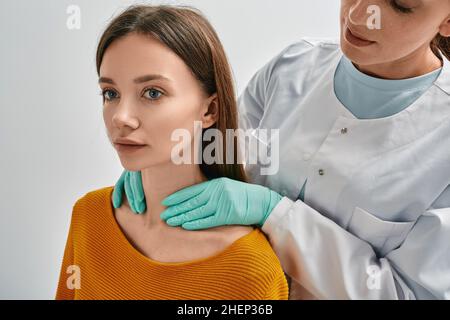 Endocrinologist checking thyroid gland of adult female patient by palpation. Woman has enlarged thyroid gland and hormones are not normal Stock Photo