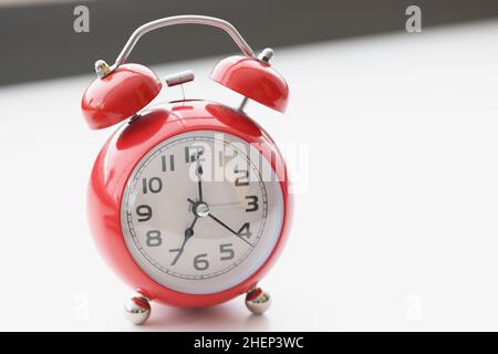 Retro red clock on white surface show seven in morning, wakeup, time for work Stock Photo