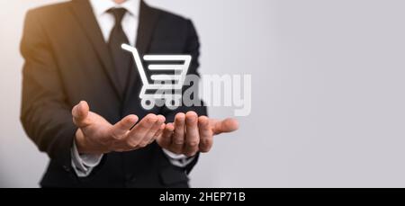 Business man hold in hand shopping cart icon.Shopping online concept.basket hologram. Online shopping, online store application in a smartphone. Digit Stock Photo