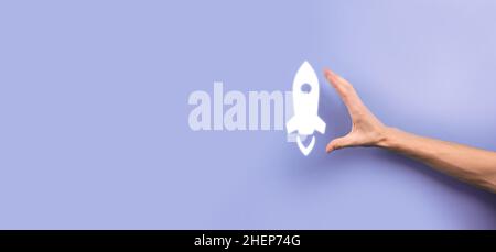 Male hand holding rocket icon that takes off, launch on blue background. rocket is launching and flying out, Business start up, Icon marketing on mode Stock Photo