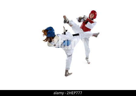 Portrait of two young women, taekwondo athletes practicing, fighting isolated over white background. Concept of sport, skills Stock Photo