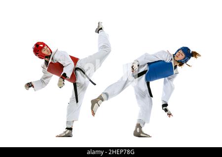 Dynamic portrait of two young women, taekwondo athletes training together isolated over white background. Concept of sport, skills Stock Photo