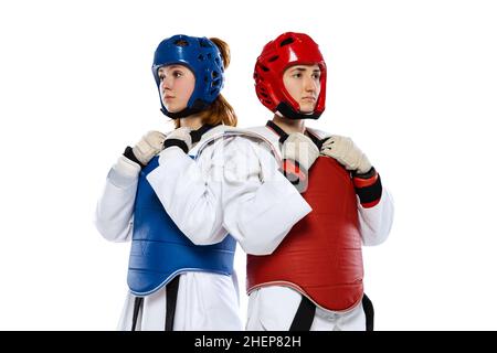 Half-length portrait of two young girls, taekwondo athletes posing isolated over white background. Concept of sport, skills Stock Photo