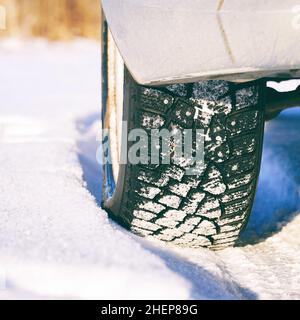 Studded winter car tires on the snow-covered road Stock Photo