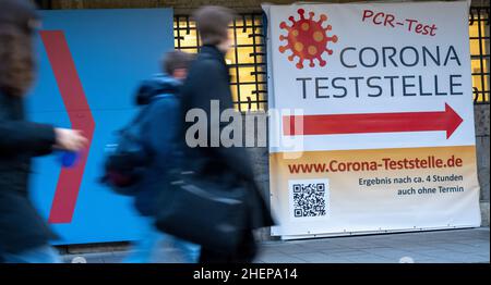 Munich, Germany. 12th Jan, 2022. Passers-by walk past signs at the Deutsches Museum pointing to a Corona test site. Credit: Peter Kneffel/dpa/Alamy Live News Stock Photo